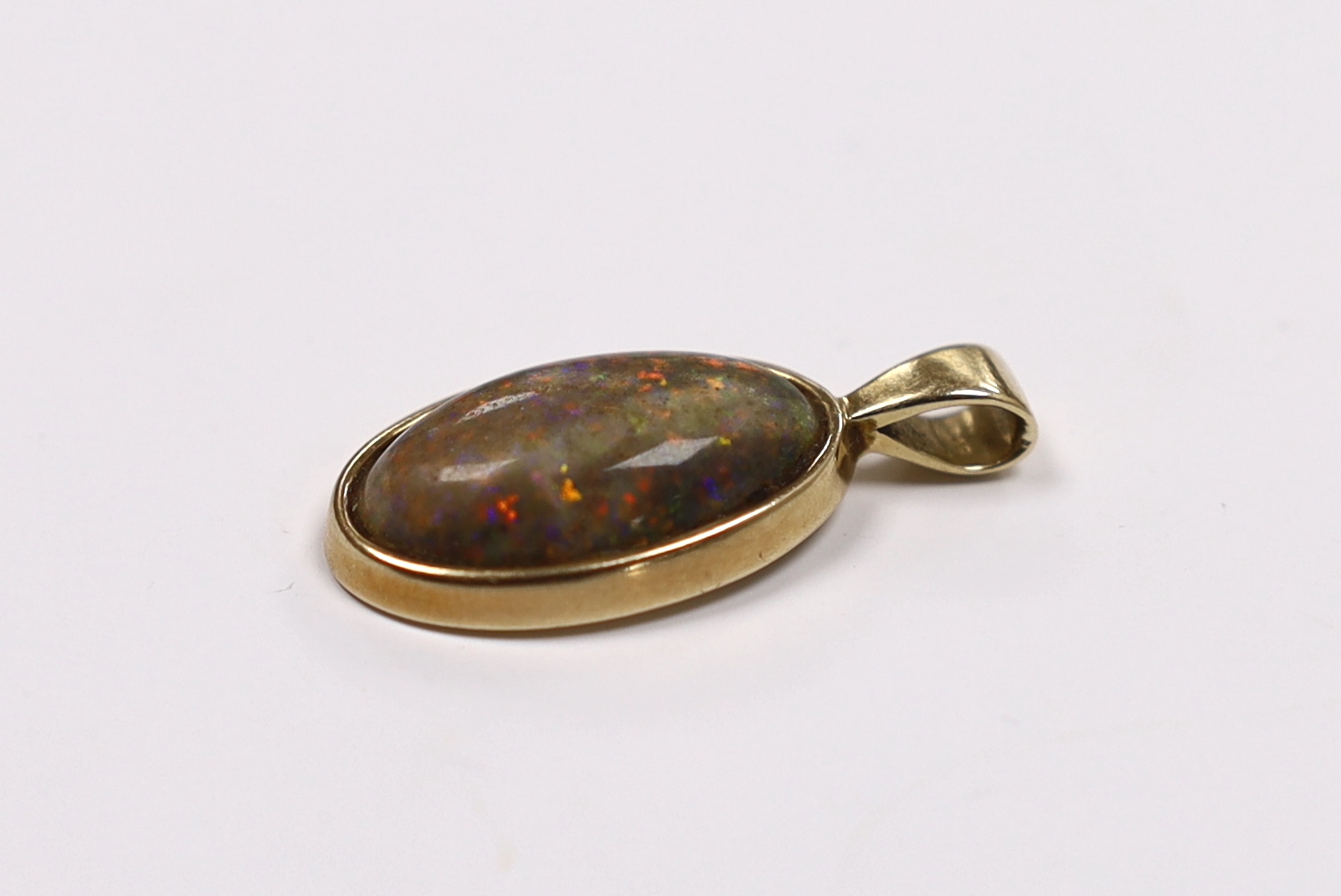 A yellow metal mounted oval black opal pendant, overall 30mm, gross weight 4 grams.